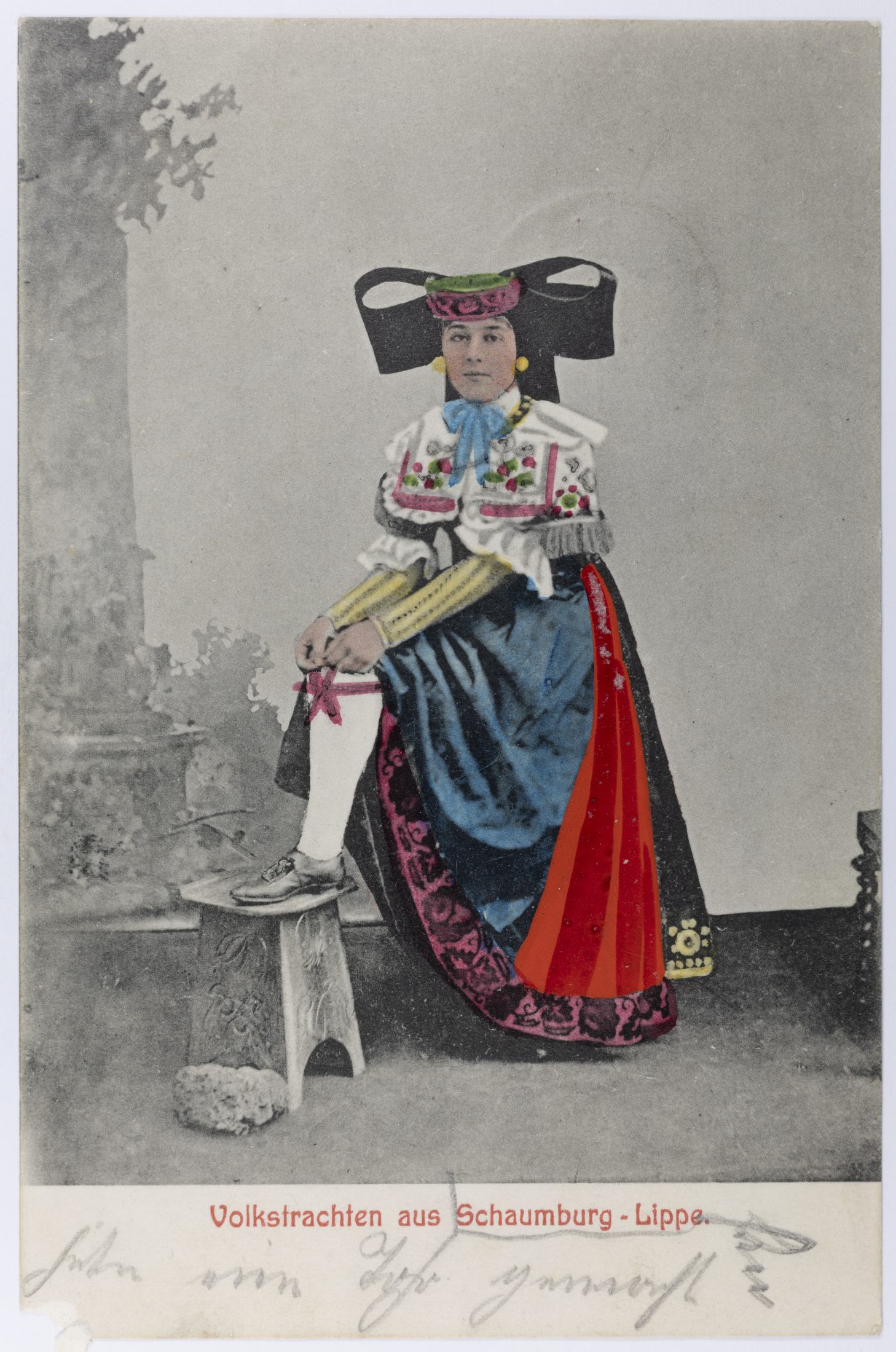 Kolorierte Ansichtskarte: Frau in Schaumburger Tracht beim Richten eines Strumpfes. Verlag F. W. Kuhlmann