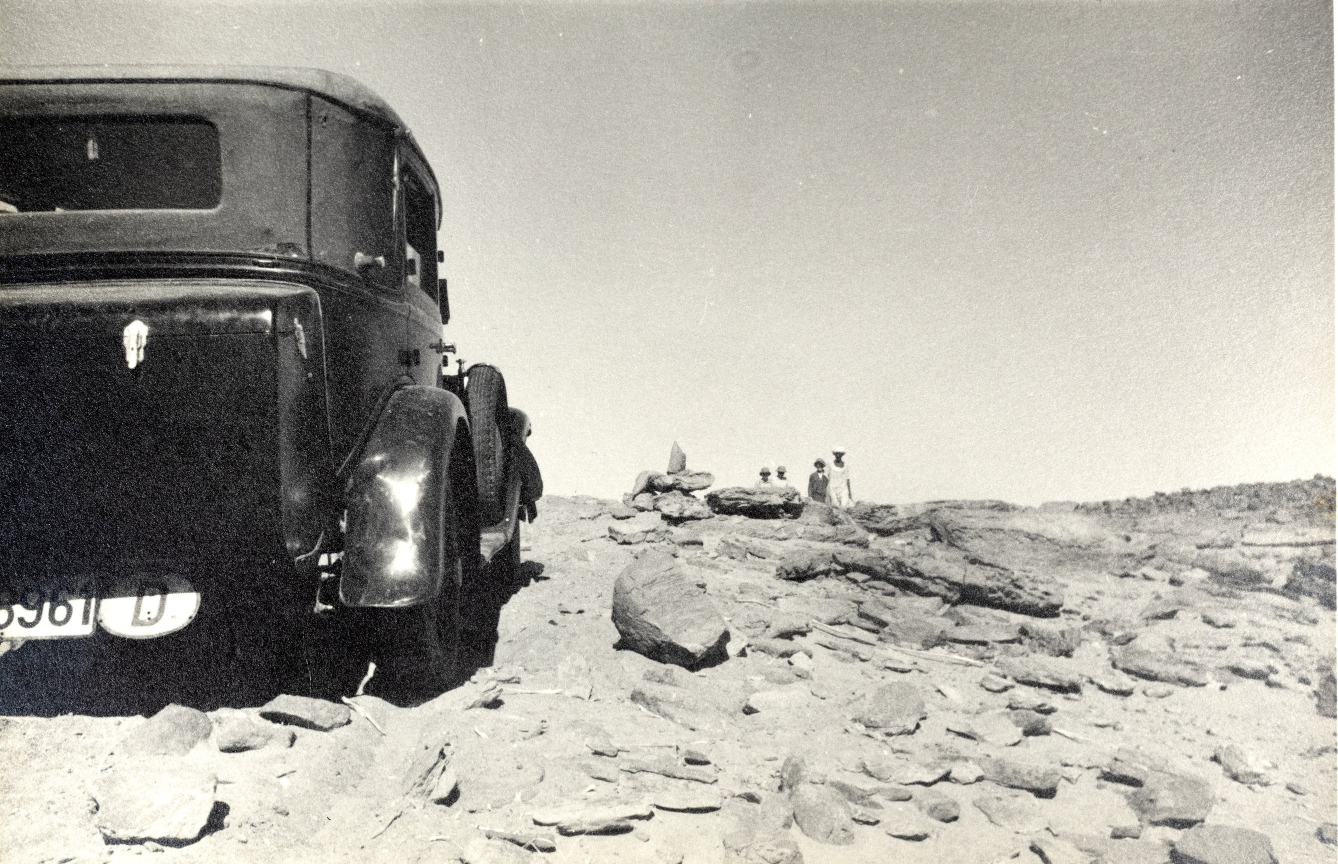 Das Expeditionsauto in einer felsigen ägyptischen Wüstenlandschaft, mit Reisenden im Hintergrund